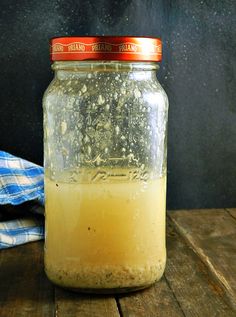 a jar filled with liquid sitting on top of a wooden table