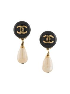 Black/white gold plated brass 1994 CC dangle clip-on earrings from Chanel Pre-Owned featuring dangle design, signature interlocking CC logo, faux-pearl detailing, circa 1994 and round upper body. Please be mindful that this piece has led a previous life, and may tell its story through minor imperfection. Purchasing this item continues its narrative, so you can be confident that you’re making a POSITIVELY CONSCIOUS choice for the planet.. Two's company. These earrings come as a pair.. | Chanel Pr Chanel Jewelry Earrings, Jewelry Accessories Ideas, Shopping Chanel, Chanel Earrings, Chanel Jewelry, Black White Gold, Earrings Black, Cc Logo, Brass Jewelry