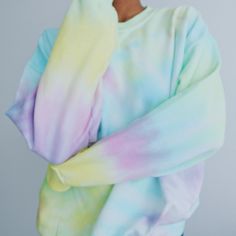 a woman with her arms crossed wearing a tie dye sweatshirt