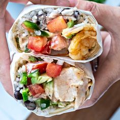 two burritos filled with different types of vegetables and meat on top of each other