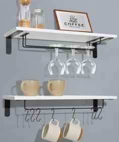 coffee cups and mugs are hanging on the wall above two shelves with wine glasses