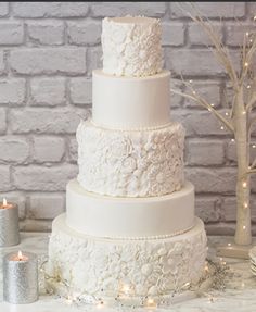 a white wedding cake sitting on top of a table next to some candles and flowers