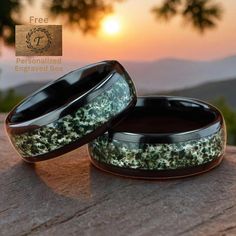 two black ceramic rings with green moss growing on them and the sun setting in the background