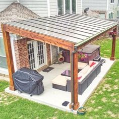 a covered patio with couches and table in the back yard, next to a house