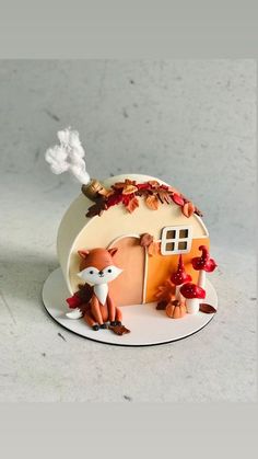 a cake that is shaped like a house with foxes and mushrooms on the outside, sitting on top of a plate