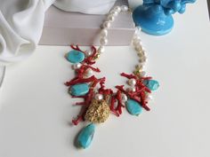 Handcrafted necklace in 925 gold-plated silver made with : - River pearls (10 mm - 12 mm), white colour; - Plain Amazonite flat stones (25 mm x 18 mm) + final drop of Amazonite (35 mm x 15 mm), teal colour; - Natural Coral sprigs, red colour; - Large 925 Gold-plated Silver stone; - Gold-plated Sterling Silver 925 chain. Gold-plated Sterling Silver 925 lobster clasp. Necklace's lenght: 48 cm + 5 cm of elongation chain * SHIPPING * Your order will be shipped within 1-3 business days from your purc Elegant Red Coral Gemstone Necklace, Elegant Turquoise Necklace With Lobster Clasp, Elegant Turquoise Necklace With Lobster Clasp For Gift, Elegant Coral Necklaces With Gemstone Beads, Luxury Pearl Necklace With Lobster Clasp As Gift, Luxury Coral Jewelry For Gifts, Luxury Coral Jewelry For Gift, Elegant Turquoise Pendant Necklace With Natural Stones, Handmade Elegant Red Coral Pearl Necklace