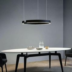 a white table with two black chairs and a light hanging over it