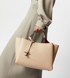 Bag in soft exposed grain leather, with Tod's logo stamped on the front, flat handles and removable shoulder strap. The interior comes with three compartments separated by zipped central pockets. An elegant creation enhanced by distinctive iconic detailing, such as the metal T Timeless pendant and T-stitching. Beige Calf Leather Bag With Top Carry Handle, Timeless Beige Calf Leather Bag, Pebbled Leather Shoulder Bag With Detachable Handle For Shopping, Pebbled Leather Bag With Detachable Handle For Shopping, Cream Rectangular Calf Leather Bag, Tan Pebbled Leather Top Handle Bag, Beige Calf Leather Top Handle Bag, Cream Calf Leather Bag For Everyday Use, Beige Calf Leather Bag With Dust Bag