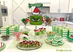 a table topped with lots of green and red desserts next to a christmas cake