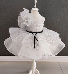 Elevate your little one's special occasion with our One Shoulder White Tutu Dress! This enchanting dress is perfect for birthdays, parties, or any celebration where your child deserves to shine. Designed with elegance and flair, it features a chic one-shoulder design and a stunning white tutu adorned with glitter. Features: Elegant One Shoulder Design: Adds a touch of sophistication and unique style. White Glittery Tutu: Sparkles beautifully, making your toddler the star of any event. Comfortabl Fitted White Dress For Birthday, White Fitted Dress For Birthday, Elegant Princess Dress For Pageant And Party Season, Elegant Princess Dress For Pageant Party Season, Elegant Ruffled Baptism Dress For Party, Elegant Glitter Tulle Pageant Dress, White Ruffled Dresses For Party Season, Fitted Princess Style Baptism Dress For Party, White Fitted Princess Dress For Dress-up