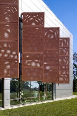 the side of a building with large windows on it's sides and grass in front