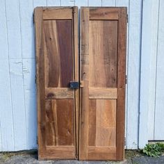 an old pair of wooden doors sitting on the side of a building