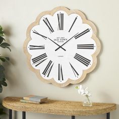 a clock on the wall with roman numerals is displayed next to a table