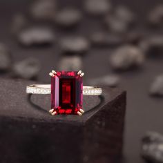 a ring with a large red stone surrounded by small white diamonds on a black surface