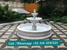 a white fountain sitting in the middle of a garden