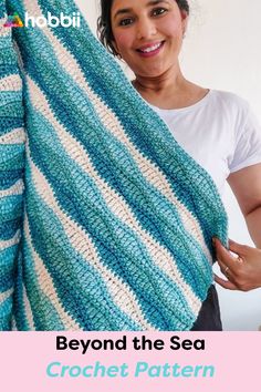 a woman holding up a blue and white striped crochet blanket with text that reads, beyond the sea crochet pattern