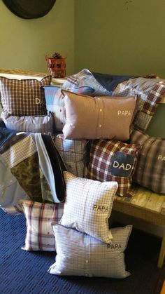 a pile of pillows sitting on top of a wooden bench in front of a wall