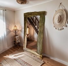 a mirror sitting on top of a wooden floor next to a wall mounted light fixture