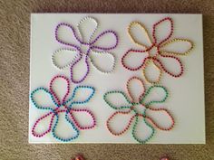 some beads are laying on the floor next to a card with four different colored flowers