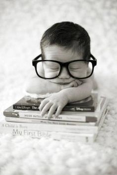 a baby wearing glasses is sleeping on some books