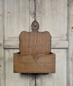 an old wooden box hanging on the side of a white door with woodgrain