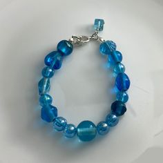 Discover the beauty of our Crystal Blue Lamp Work Glass Bead Bracelet, a mesmerizing piece of handcrafted jewelry that adds a touch of elegance to any ensemble. Each glass bead is skillfully crafted with intricate details, showcasing the captivating shades of crystal blue that catch the light beautifully. 🌟 Handcrafted Elegance 🌟 Indulge in the artistry of this lamp work glass bead bracelet, lovingly handcrafted to create a one-of-a-kind accessory. The combination of exquisite craftsmanship and alluring crystal blue hues makes this bracelet a true statement piece.🛍️ Product Details 🛍️ Material: Lamp Work Glass Beads Bead Color: Crystal Blue Bracelet Length: Adjustable to fit most wrists Clasp: Secure Toogle Clasp Crystal Blue Bracelet, Lamp Work Glass Bead Jewelry, Handcrafted Accessor Handmade Light Blue Beaded Bracelets, Turquoise Beaded Glass Jewelry, Blue Crystal Bracelet With Spacer Beads, Bohemian Blue Czech Glass Bracelets, Blue Round Beaded Bracelets With Faceted Beads, Blue Stretch Bracelet With Polished Beads As Gift, Adjustable Blue Beaded Bracelets With Large Beads, Blue Spiritual Bracelets With Large Beads, Gift Blue Stretch Bracelet With Polished Beads