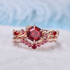 an engagement ring with a red stone surrounded by white diamonds and pink sapphires on top