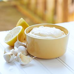 a bowl of whipped cream next to some lemons and garlic on a white table