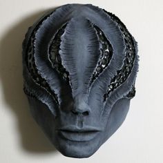 an alien head is shown against a white wall