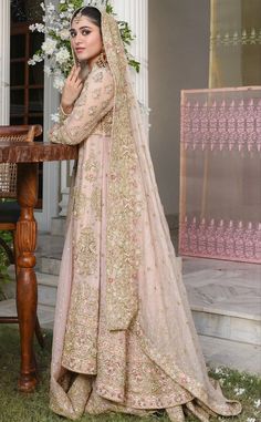 a woman standing in front of a table wearing a bridal gown and veil with flowers on it