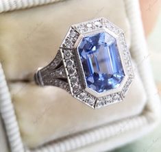 an engagement ring with a large blue stone surrounded by small white diamonds on a cushion