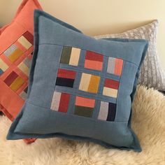 two decorative pillows on a white furnishing with one blue and the other orange