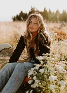 a woman sitting on the ground in a field