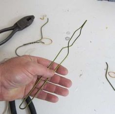 a hand is holding some wire on a table