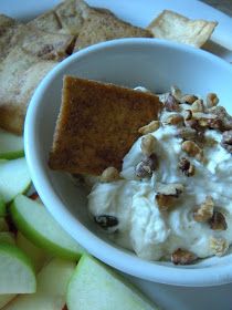 a white bowl filled with food next to sliced apples and crackers on a plate