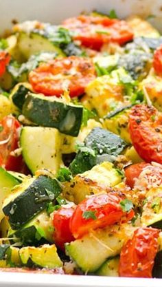 a casserole dish filled with zucchini, tomatoes and other veggies