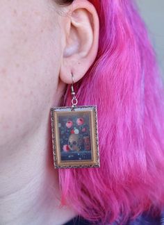 These fine art earrings depict a still life painting of a skull and vibrant florals with an ornate gold frame by Jan Van Kessel the Elder in 1670.  These unique drop earrings are the perfect gift for a witch, art lover, Halloween lover, painter, or history buff in your life. Wear them to a party, class, or to a museum! (Or anywhere else for that matter) These earrings are made of acrylic, an epoxy layer, and hypoallergenic nickel-free stainless steel earring hooks.  You will receive:  1 pair of Dark Academia Earrings, Academia Earrings, Artist Earrings, Vanitas Still Life, Dark Academia Jewelry, Painting Earrings, Frame Earrings, Skull And Flowers, Artistic Earrings