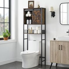 a white toilet sitting next to a wooden cabinet in a bathroom under a large window