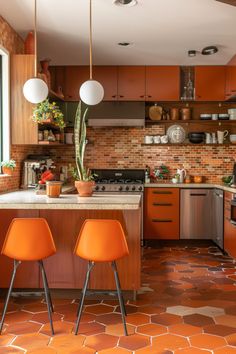 two orange chairs sit in front of an island with potted plants and pots on it