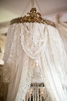 a chandelier hanging from the ceiling in a room with white curtains and lace