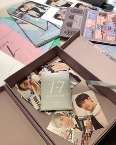 an open box filled with photos and cards on top of a wooden table next to other items