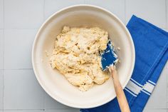 a white bowl filled with food next to a blue towel on top of a table