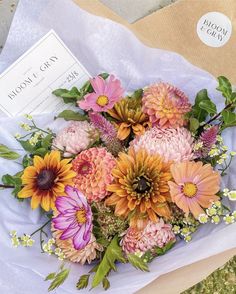 a bouquet of flowers sitting on top of a white table cloth next to a sign