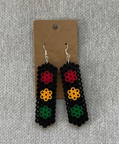 a pair of black and red earrings with flowers on them sitting on top of a piece of paper