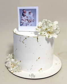 a white cake with flowers on top and a photo in the middle that has been placed on it