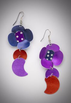 two pairs of earrings with purple, red and blue designs on them are hanging from silver hooks