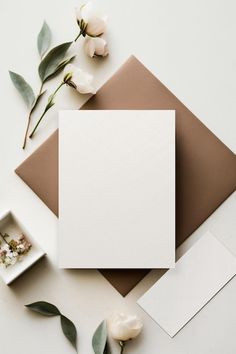 an empty card, envelope and flowers on a white table with some cards in the middle