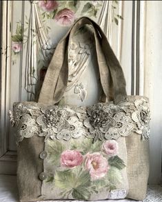 a handbag with pink flowers on it hanging from a wall next to a white door