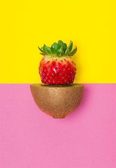 a strawberry sitting on top of a wooden object in front of a yellow and pink background