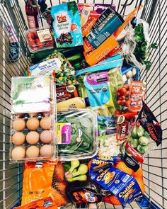 a shopping cart filled with lots of groceries and eggs in it's side basket